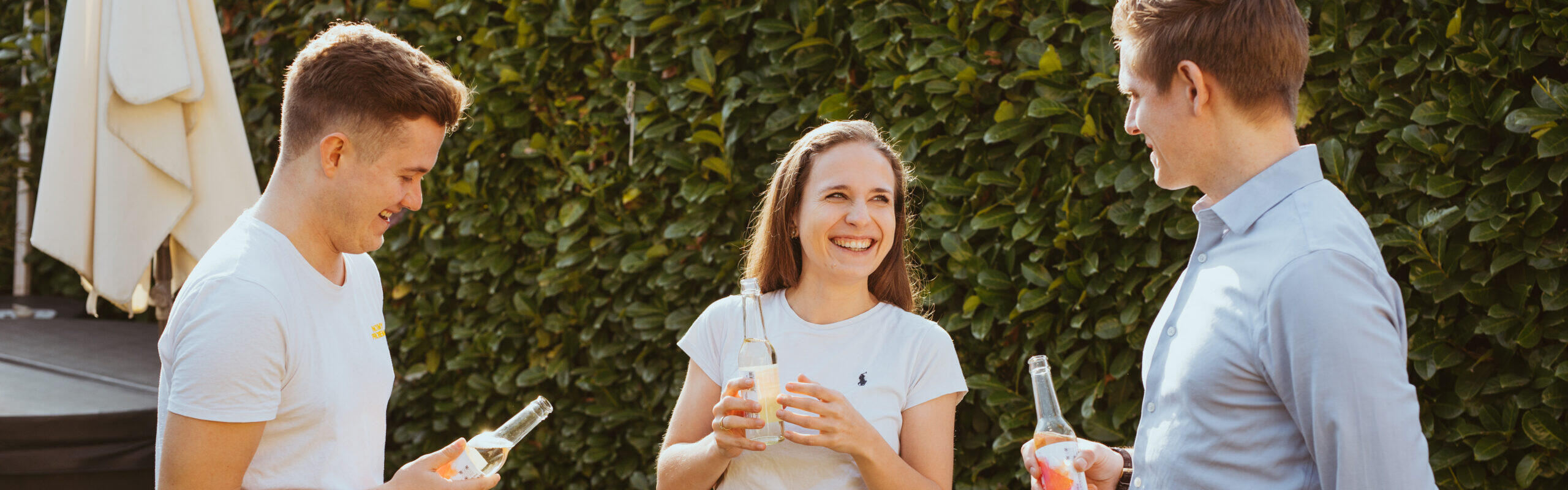 Teamfoto der Gründer des Unternehmens Rheingauer Tropfen, drei Personen mit einer Flasche ONE, einem Wein-Aperitif aus dem Rheingau